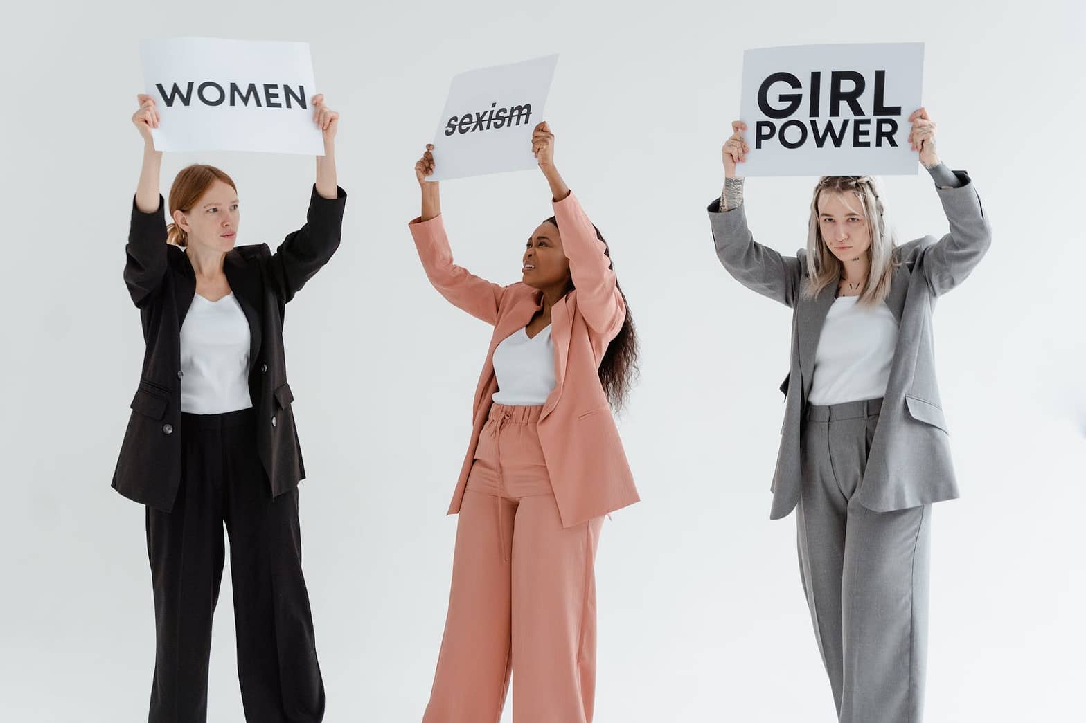 women in blazer and pants raising placards